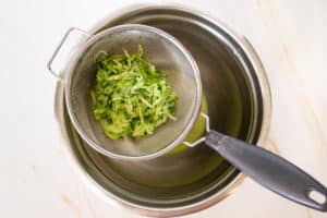 grated cucumber in a colander over a bowl