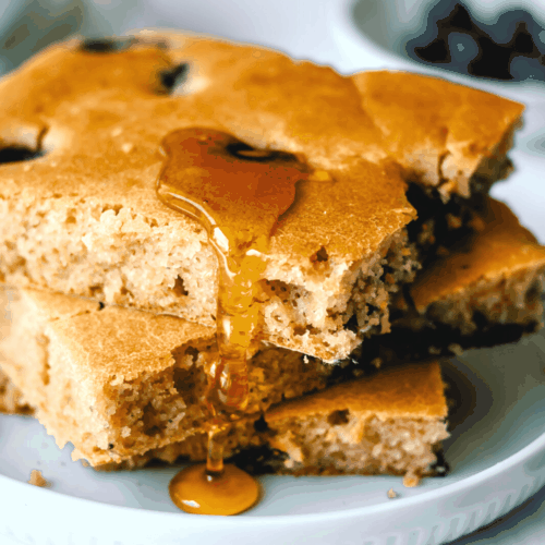 stack of blueberry sheet pan pancakes with syrup dripping down