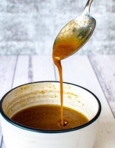 maple balsamic dressing dripping off a spoon into a bowl
