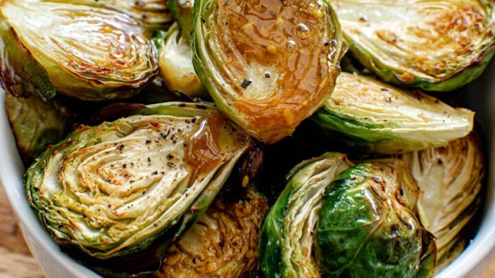bowl of roasted brussels sprouts drizzled with balsamic maple dressing