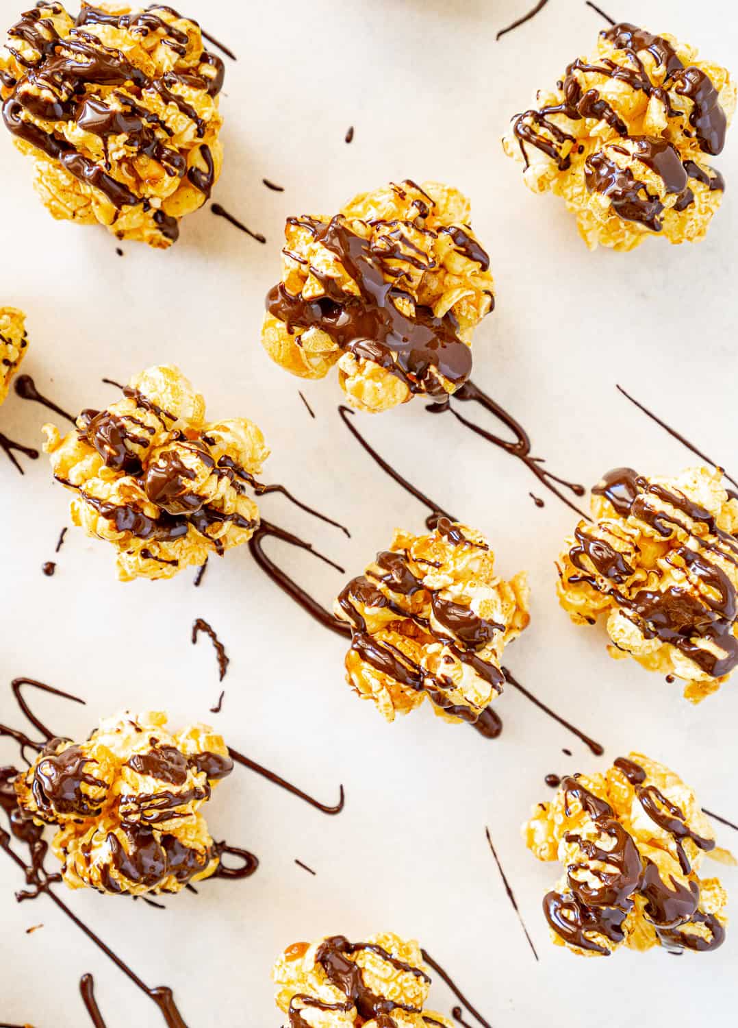 drizzled dark chocolate over popcorn balls on parchment paper