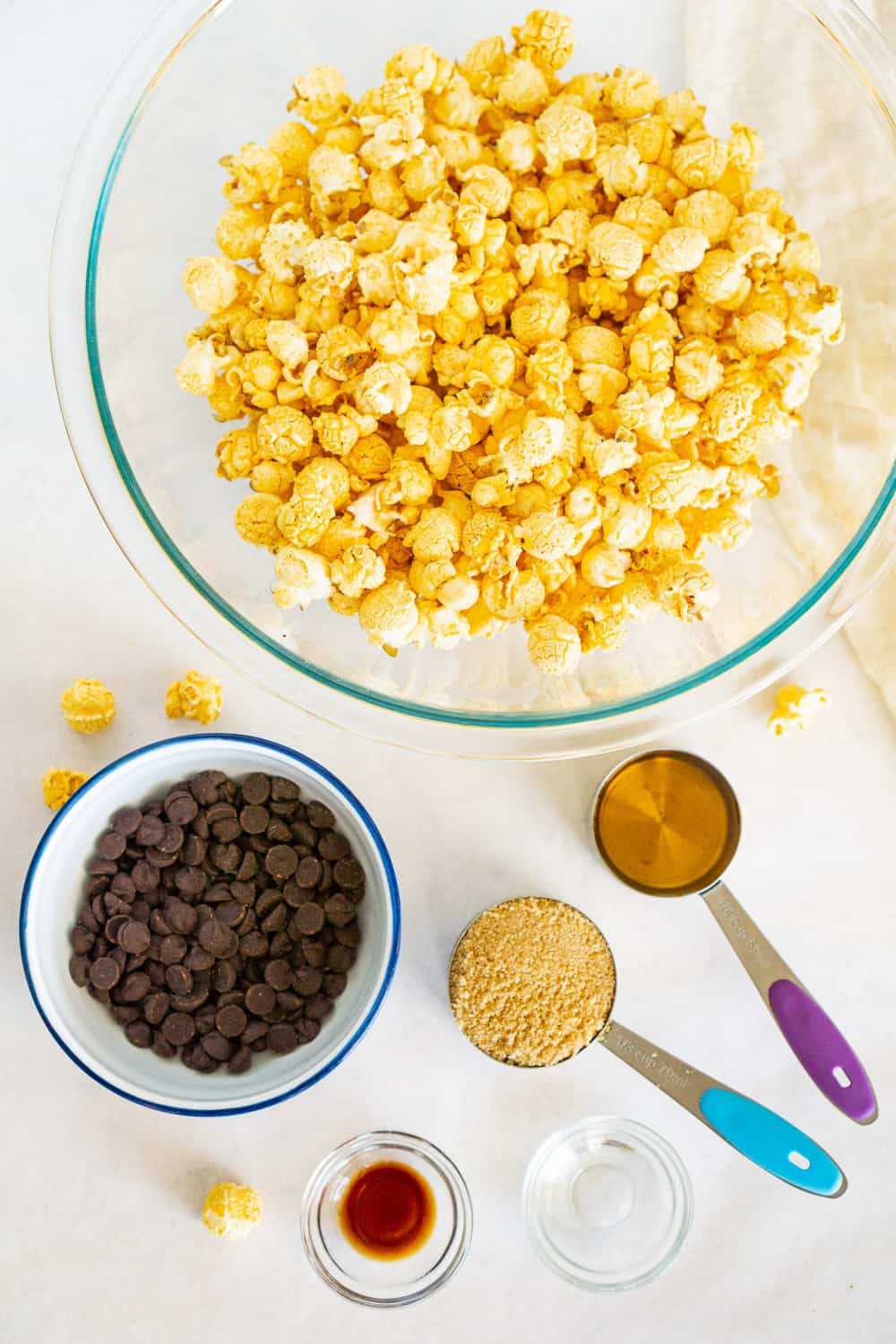 ingredients to make vegan chocolate popcorn balls: popcorn, dark chocolate, maple syrup, brown sugar, vanilla