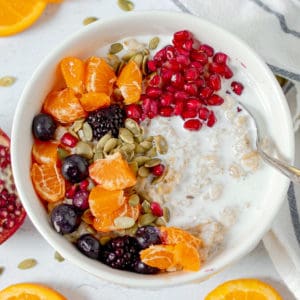 bowl of vegan oatmeal with pomegranate oranges, berries