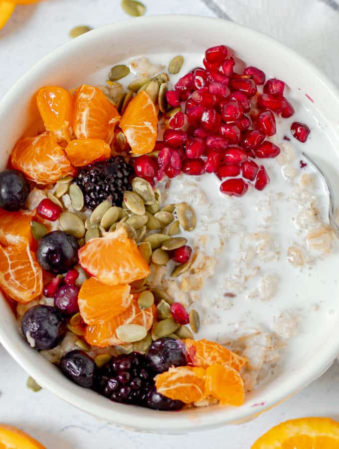 bowl of vegan oatmeal with pomegranate oranges, berries