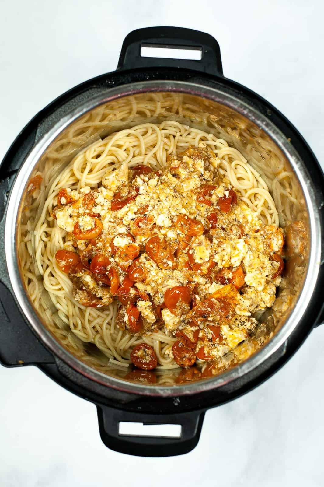 Mixing cooked spaghetti in the Instant Pot with baked feta.