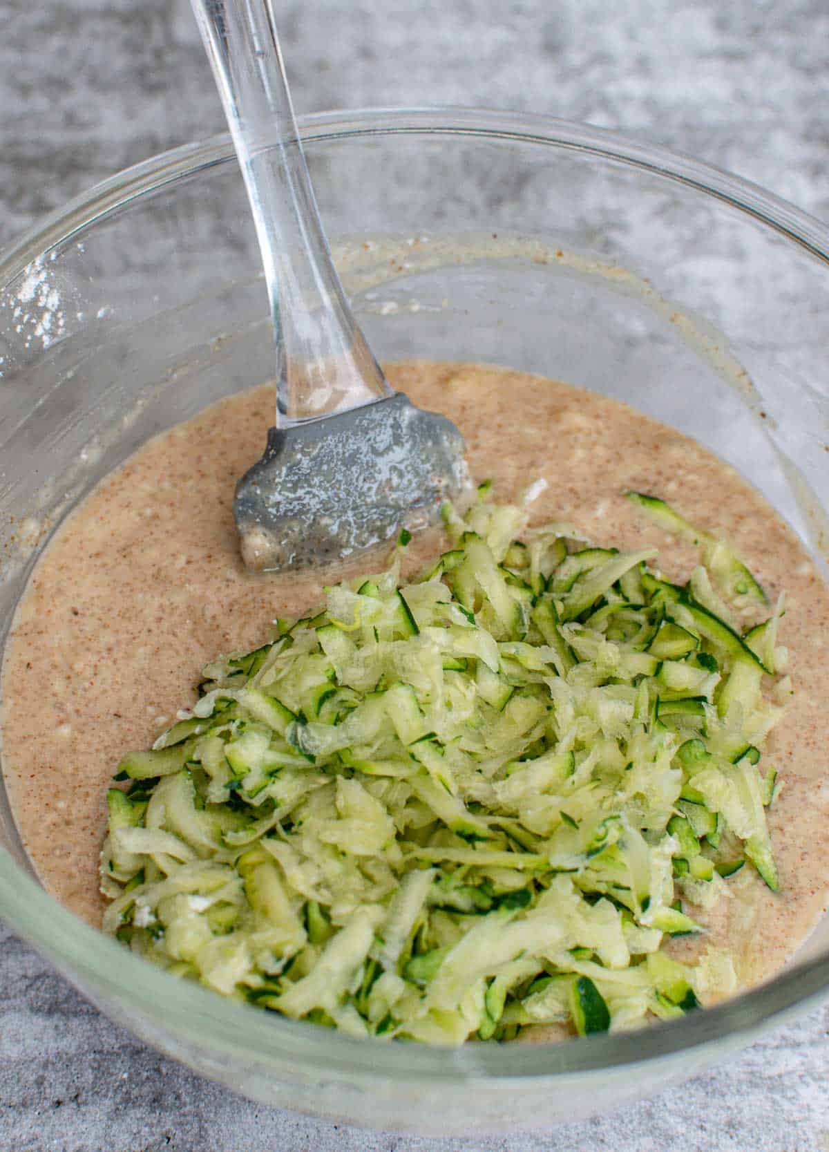 Muffin batter with shredded zucchini in a bowl.