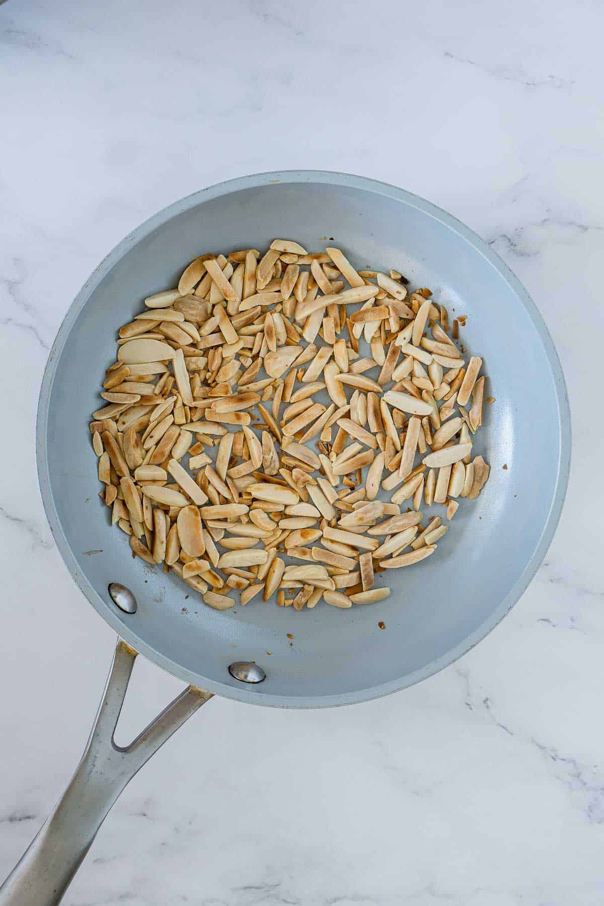 Slivered almonds toasting in a pan.