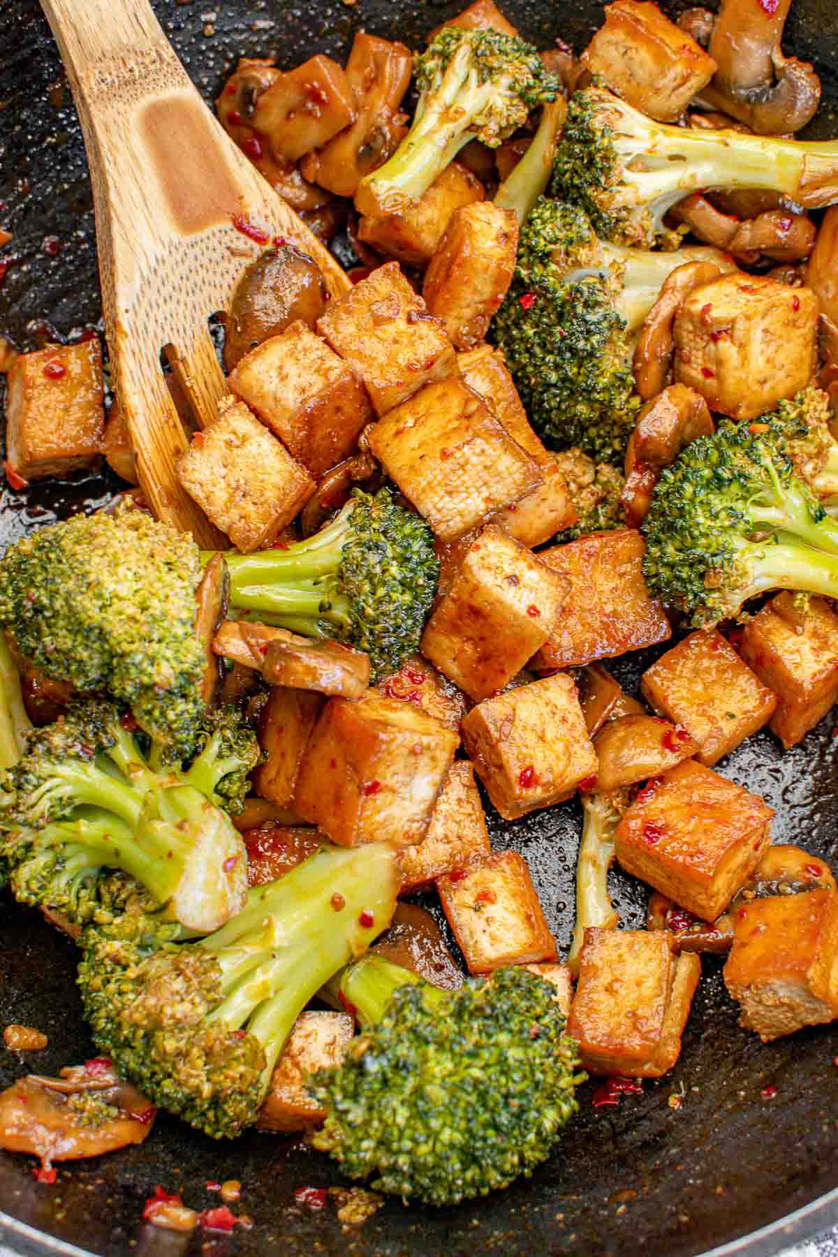 Broccoli and cubed fried tofu in a wok.