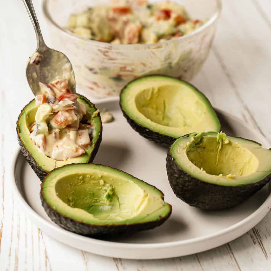 Stuffing avocados with vegan cucumber tomato salad.