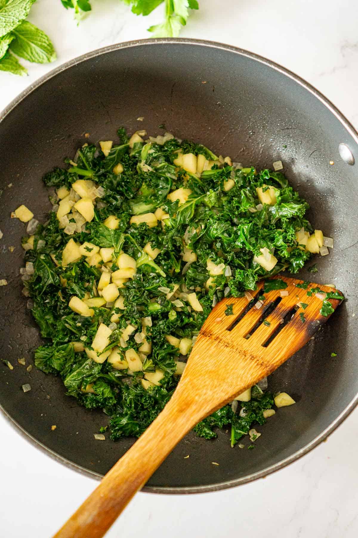 Sauteing kale and apples in a pan.