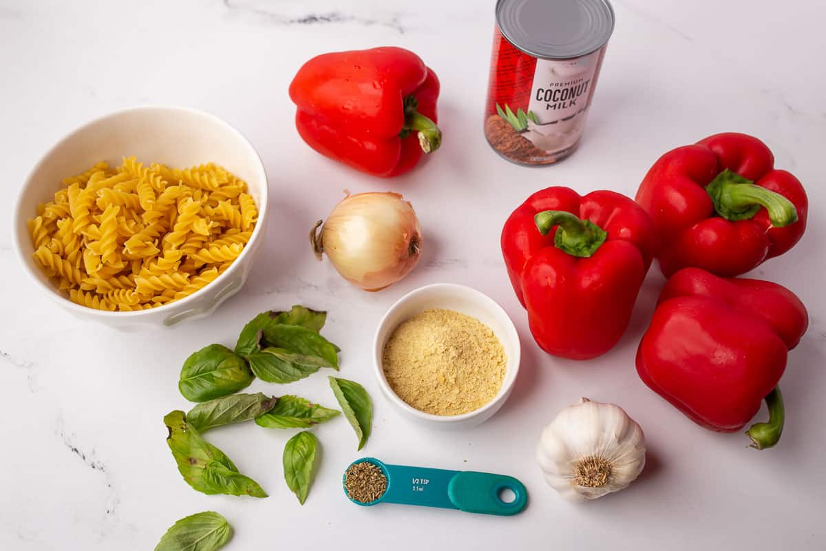 Ingredients to make vegan red pepper pasta sauce: red bell peppers, onion, garlic, coconut milk nutritional yeast, vegan chicken broth.