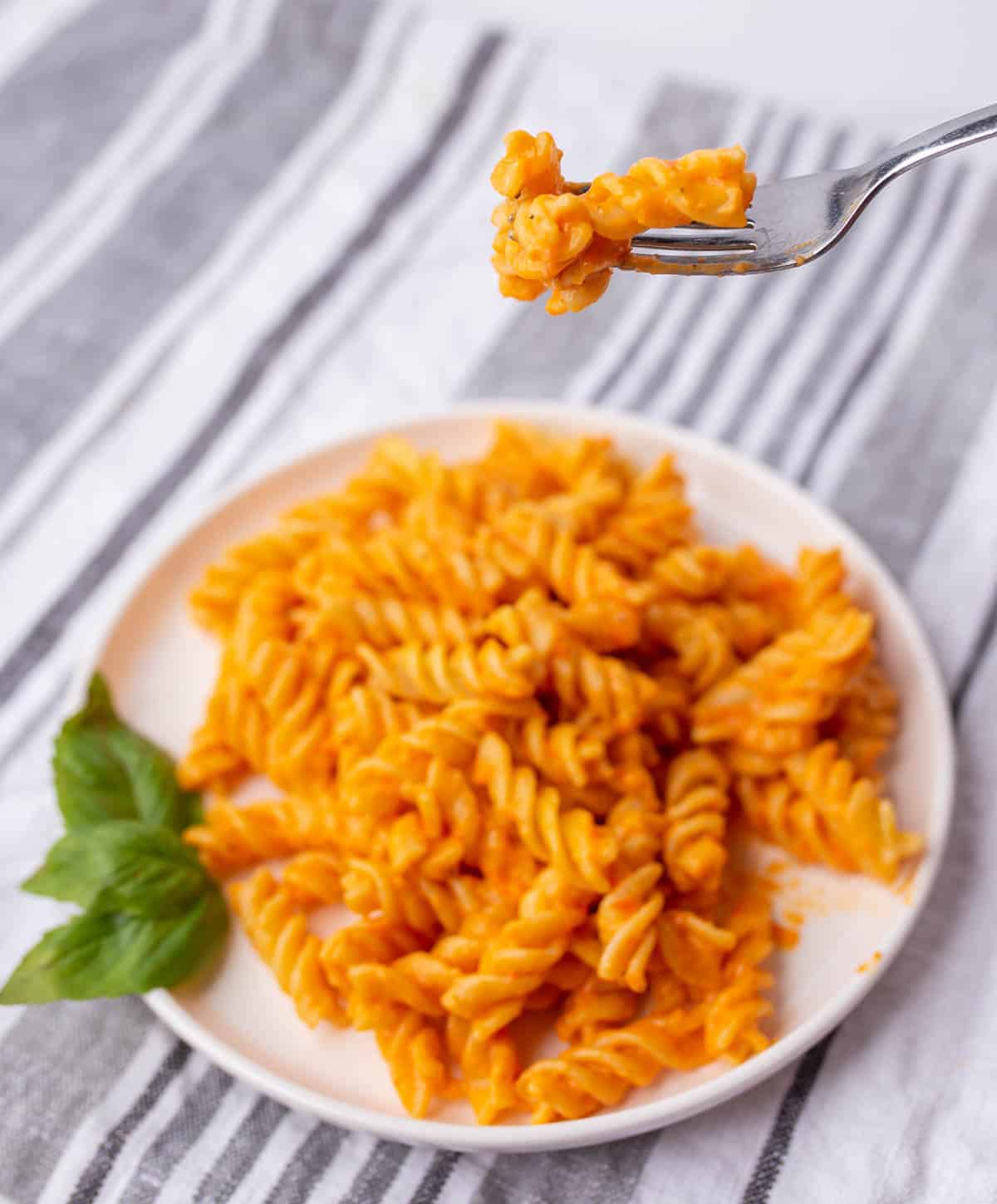 Fork holding a few pieces of pasta with roasted pepper sauce.