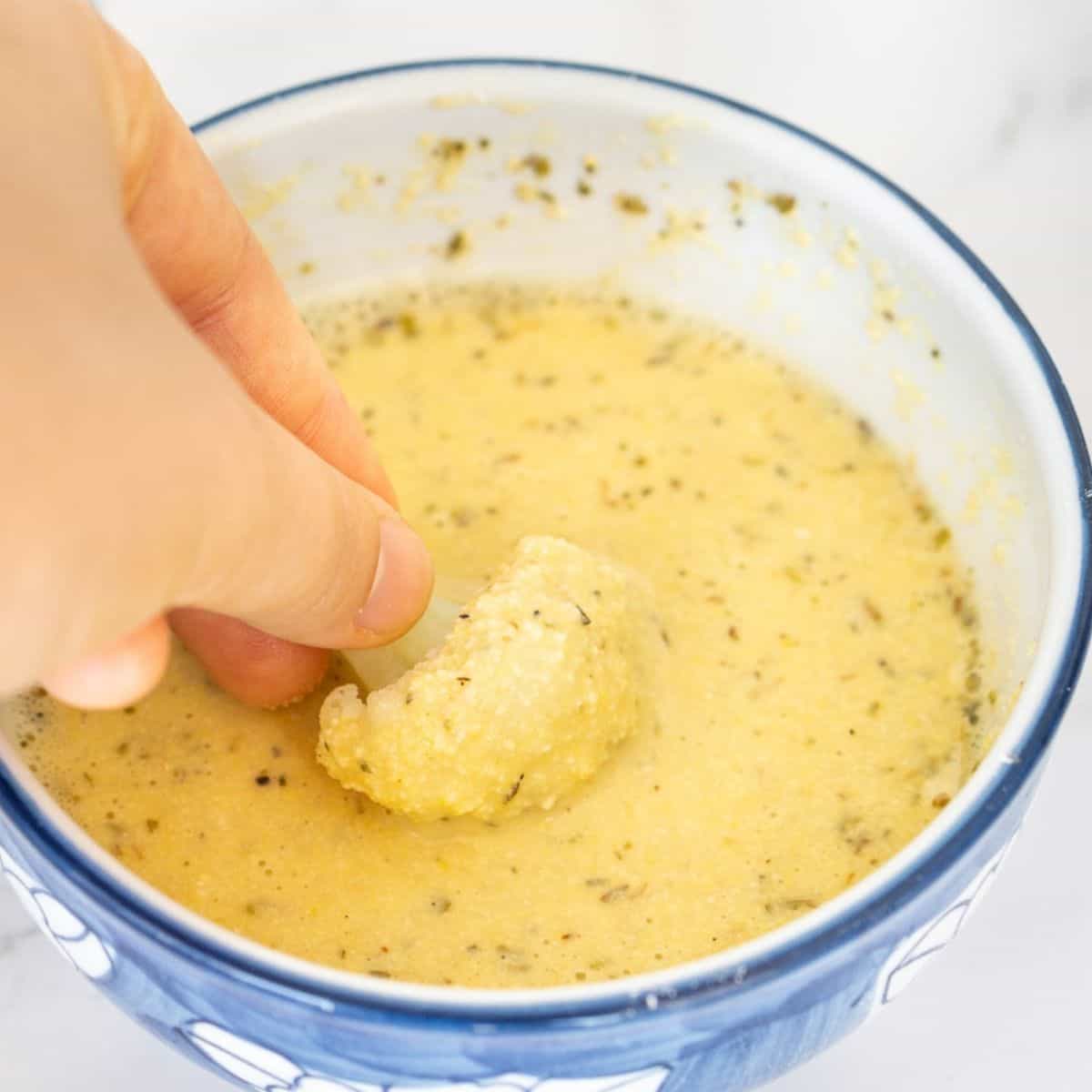 Dipping cauliflower into vegan egg substitute made with chickpea flour.