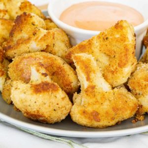 Crispy fried cauliflower on a plate with vegan dipping sauce.