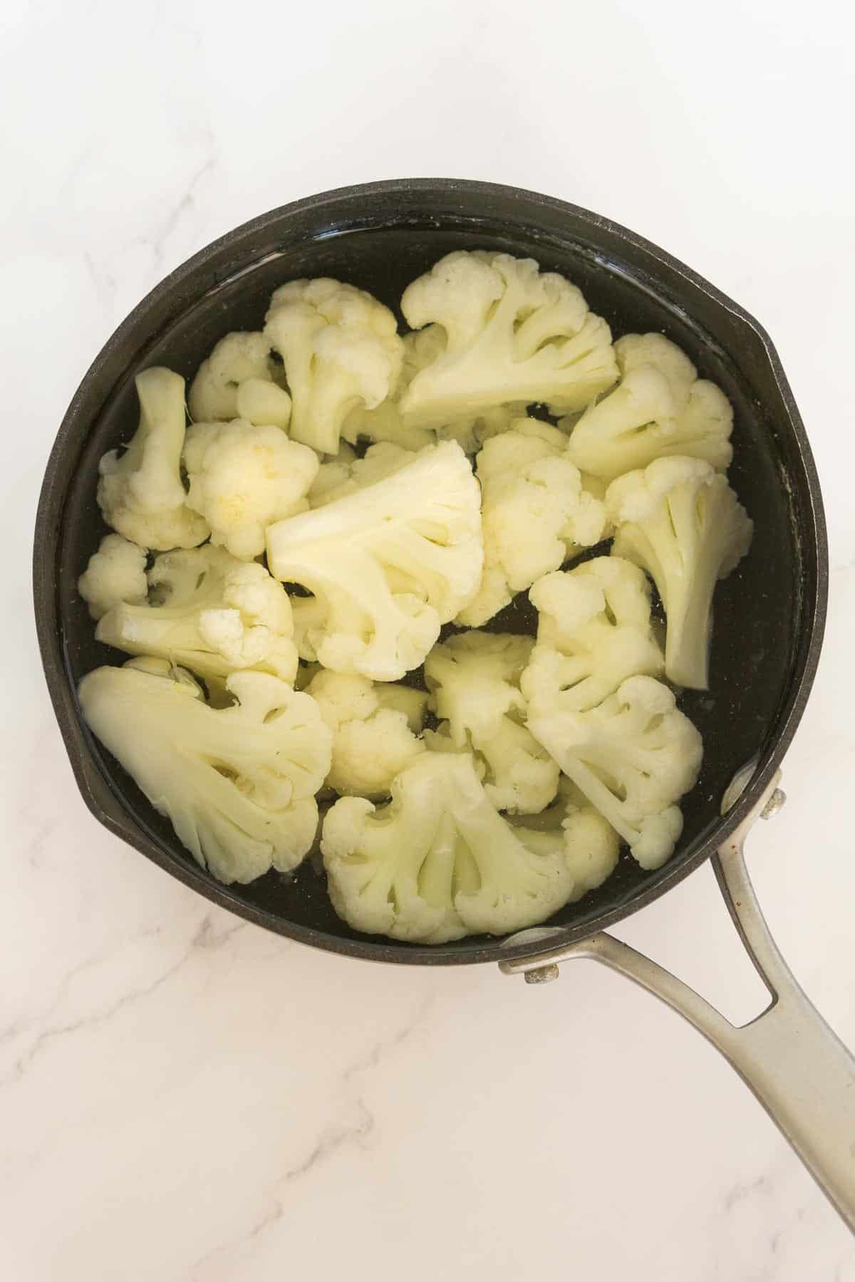 Par-boiling cauliflower florets in pot.