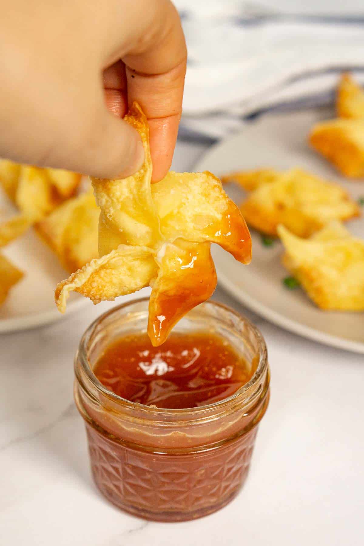 Dipping vegan rangoon into sweet and sour sauce.