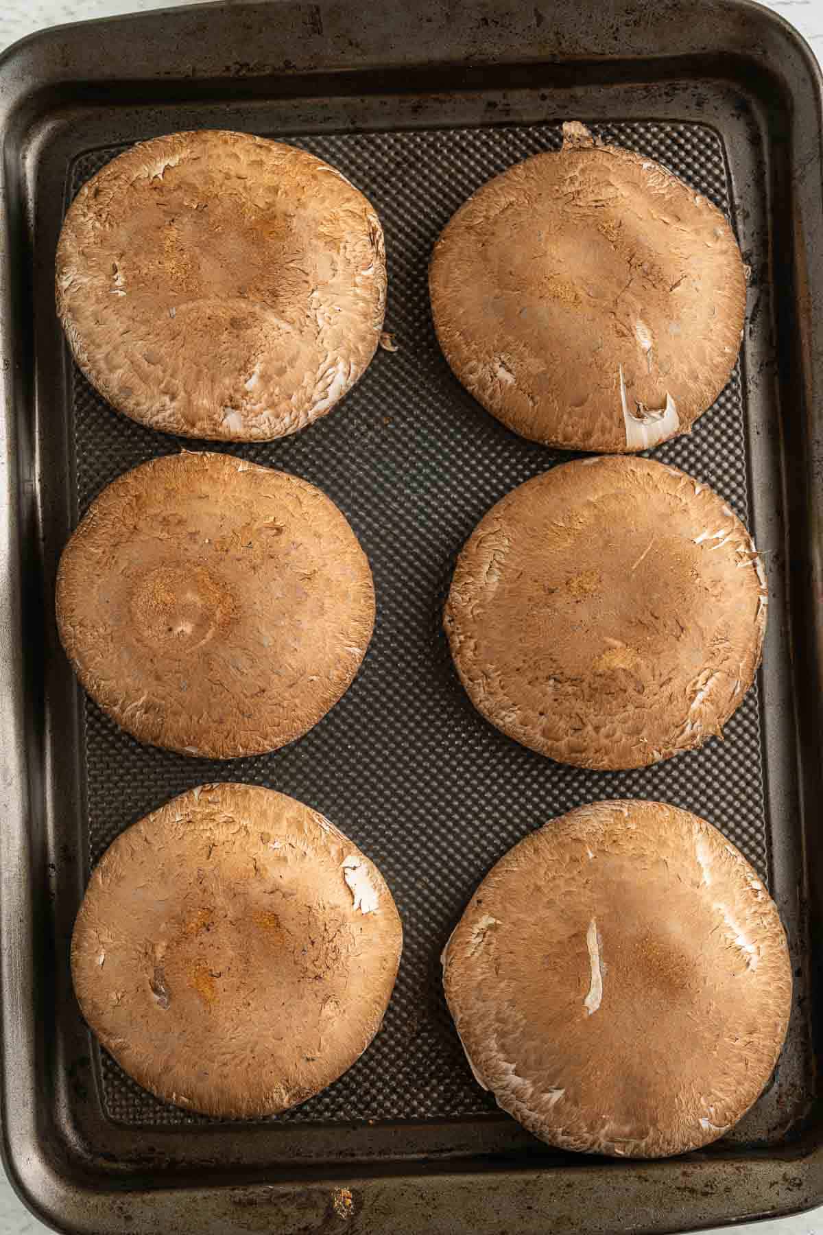 Upside down portobello caps on a baking sheet.