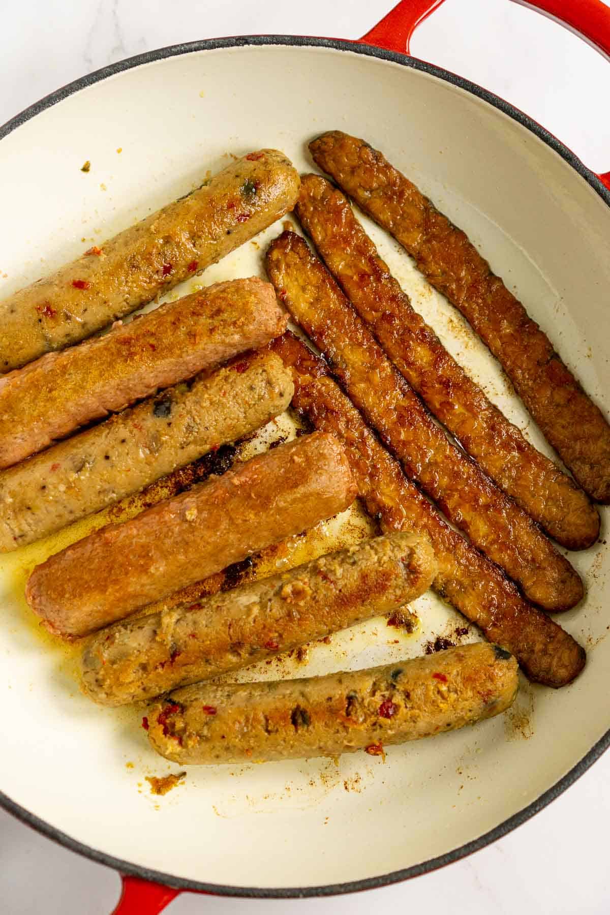 Browning vegan sausage in a casserole pan.