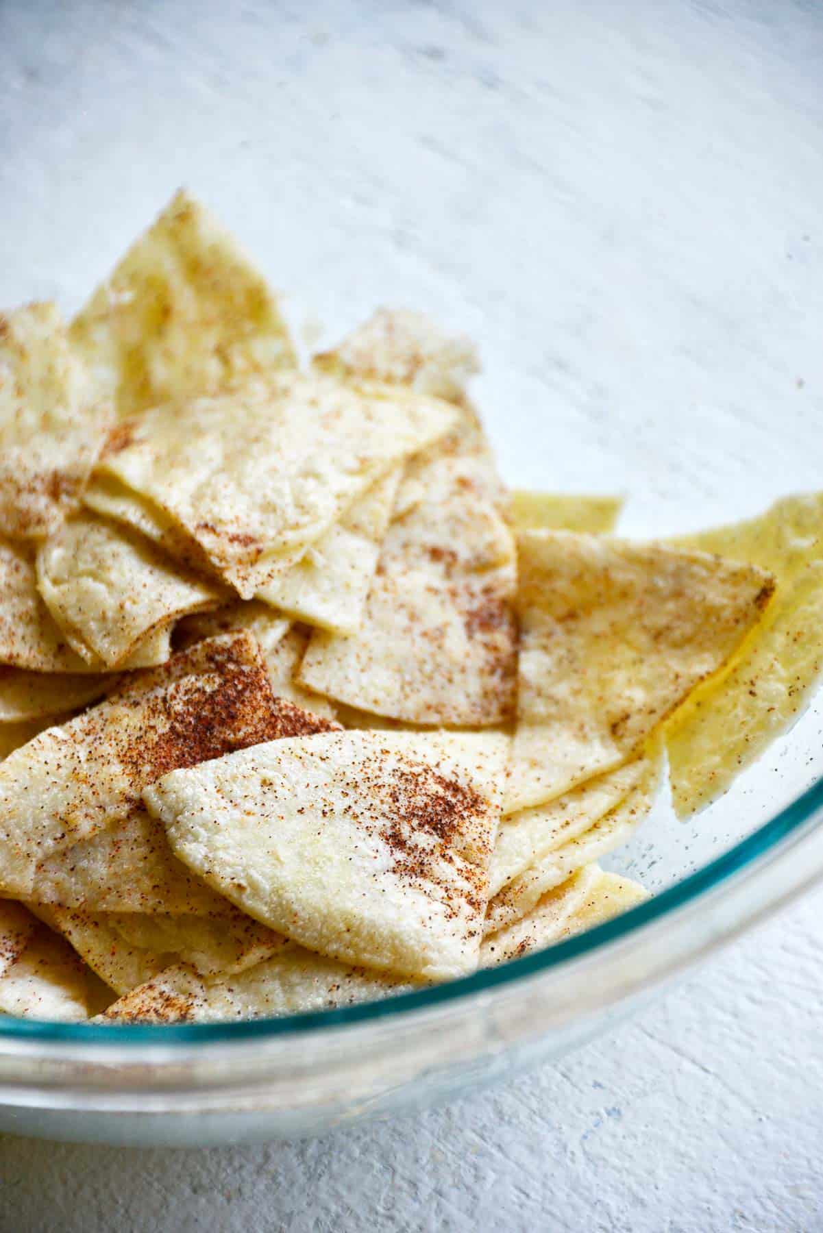 Tortilla wedges tossed with seasonings in a bowl