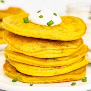 Plate of savory vegan pancakes with a dollop of vegan sour cream.