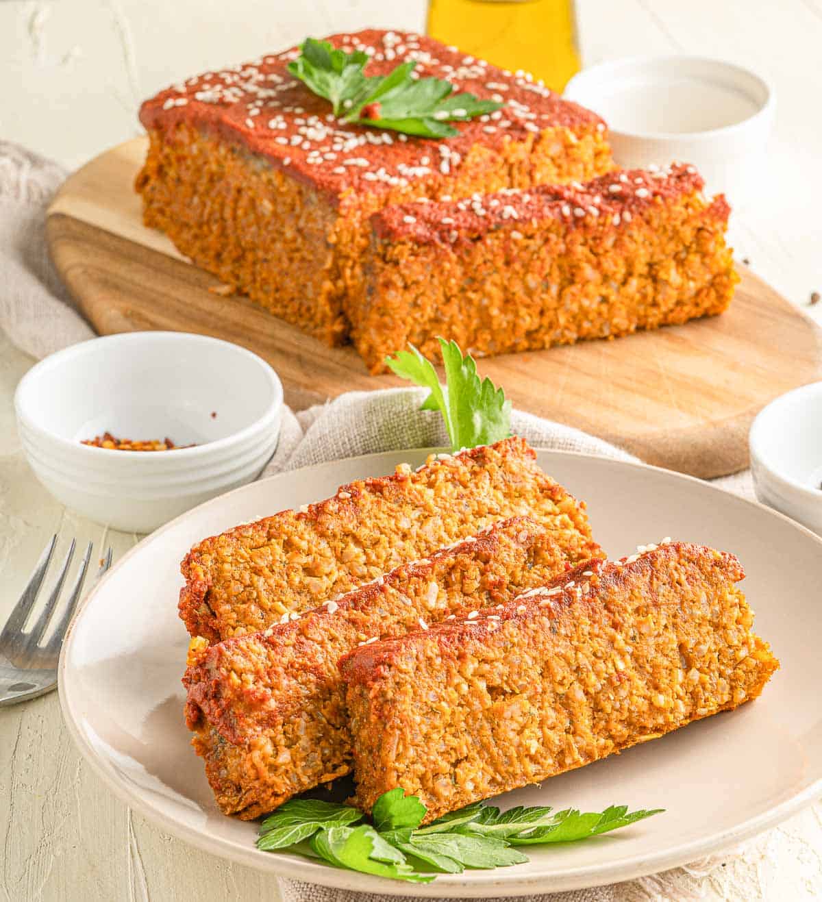 Sliced vegan loaf on a plate with the loaf in the background.