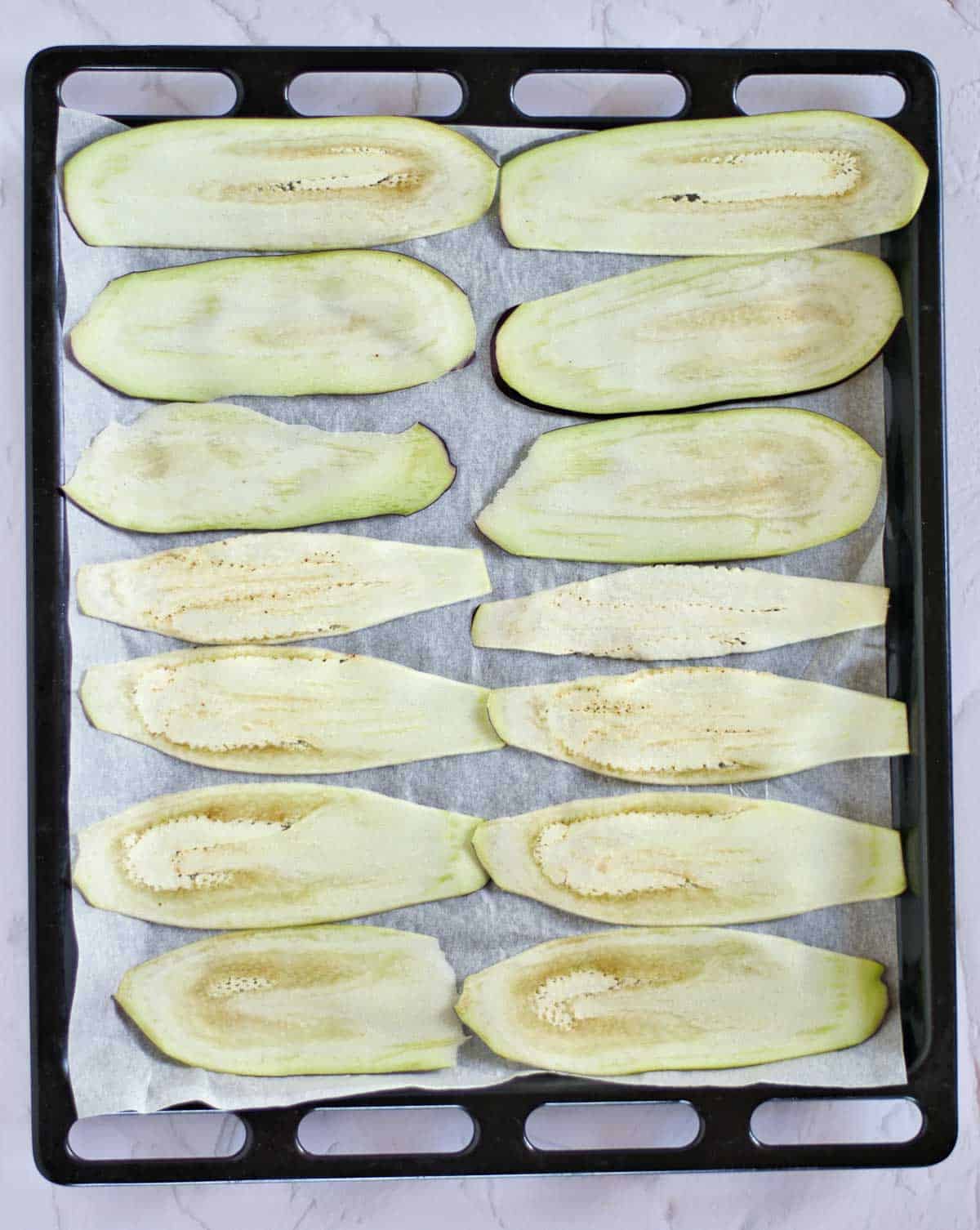 Thinly sliced eggplant on a baking sheet