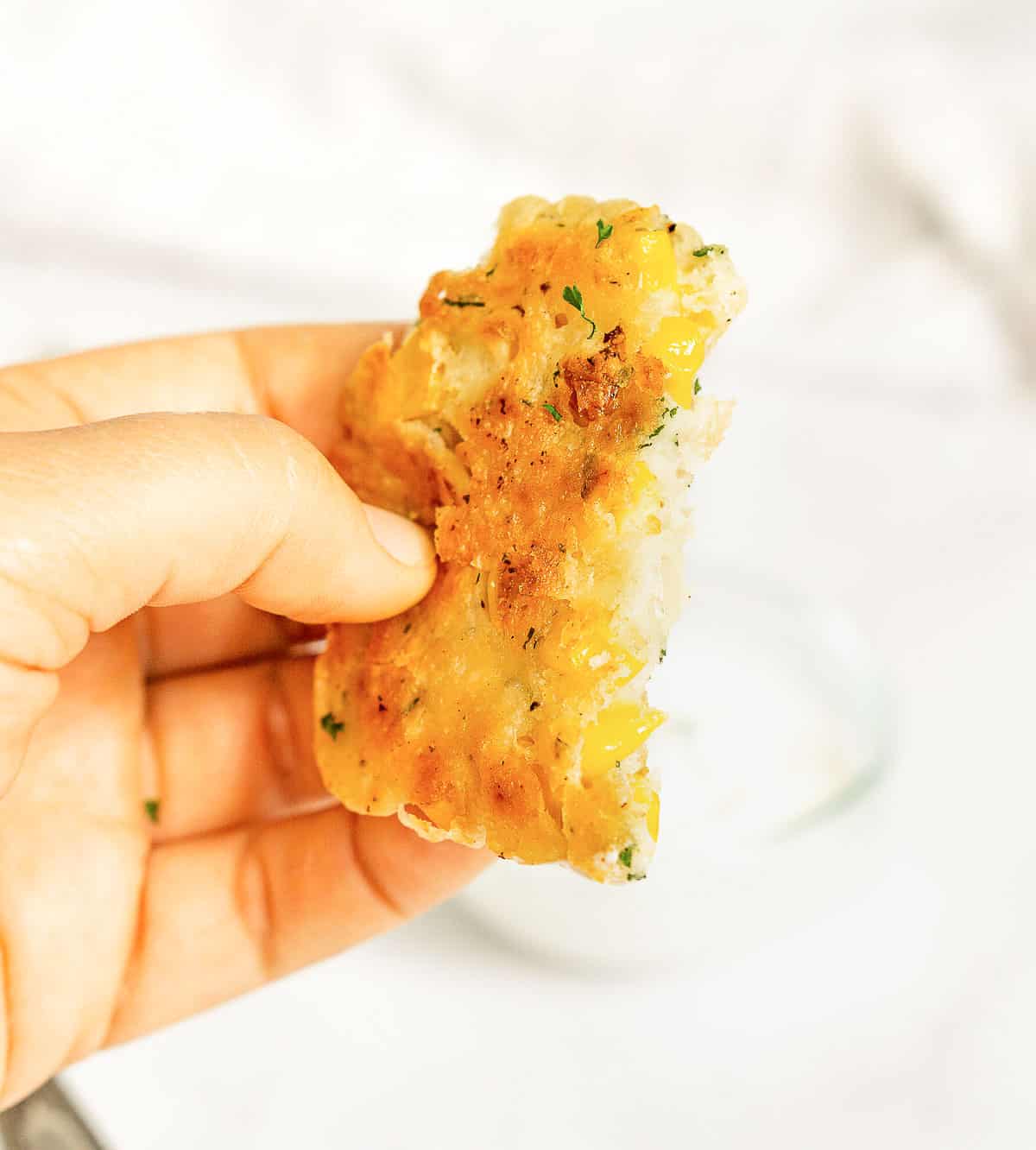 Hand holding crispy corn fritter to show texture