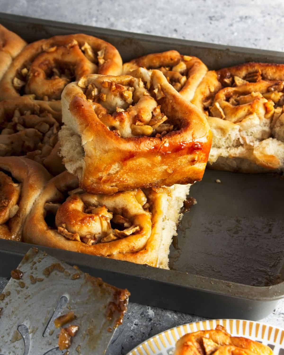Apple sticky bun with walnuts on top of a baking sheet