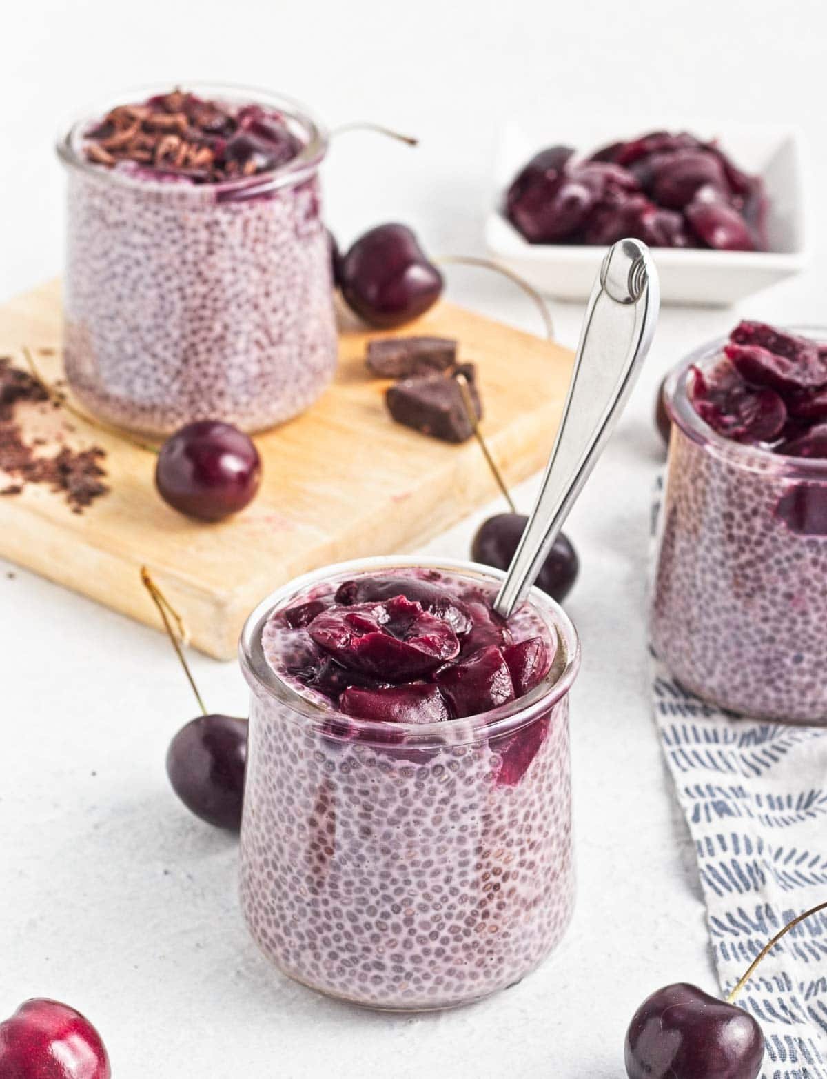 Cherry Chia Puddings in jars topped with cherry compote and shaved chocolate
