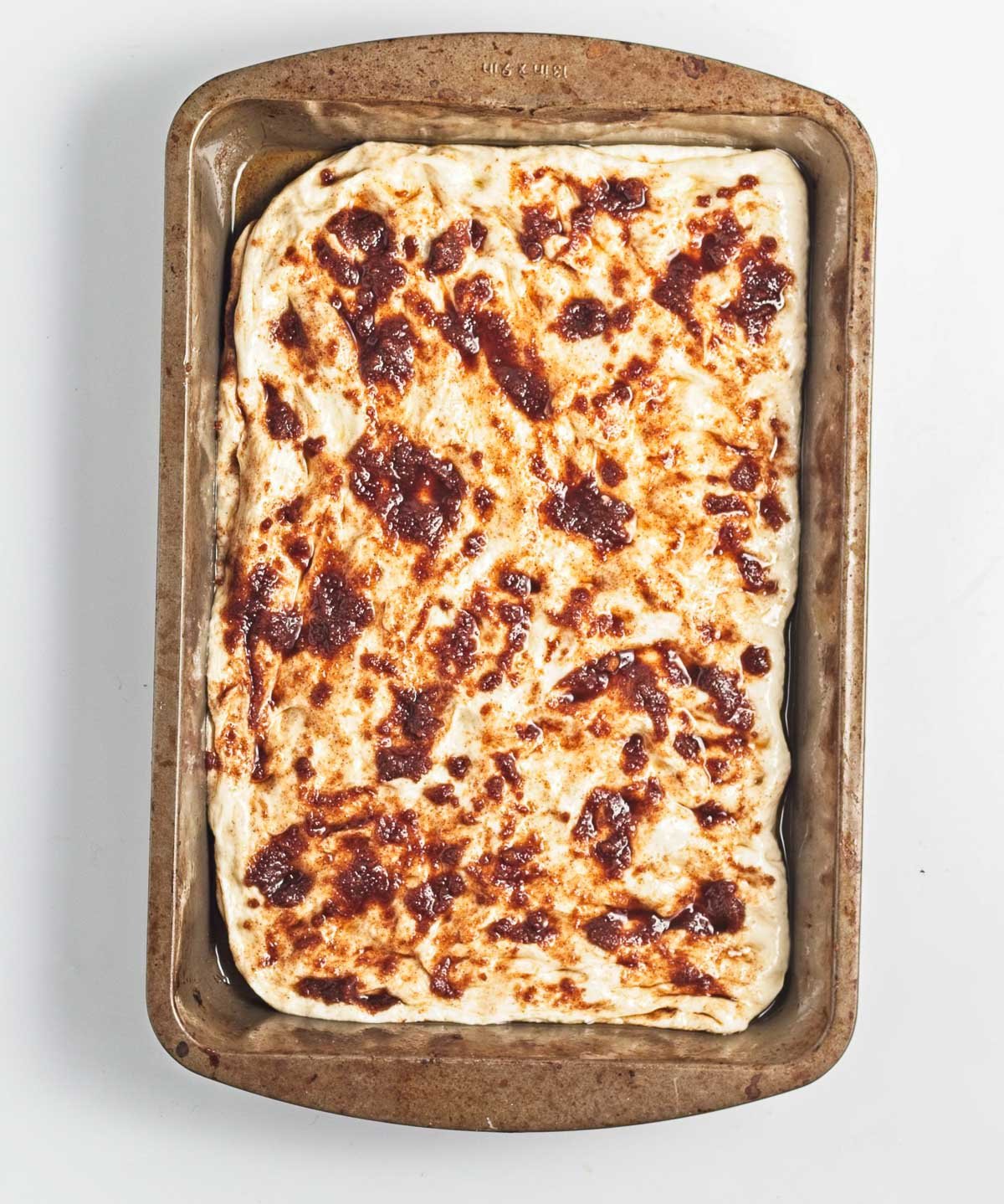 Cinnamon sugar paste spread over focaccia dough